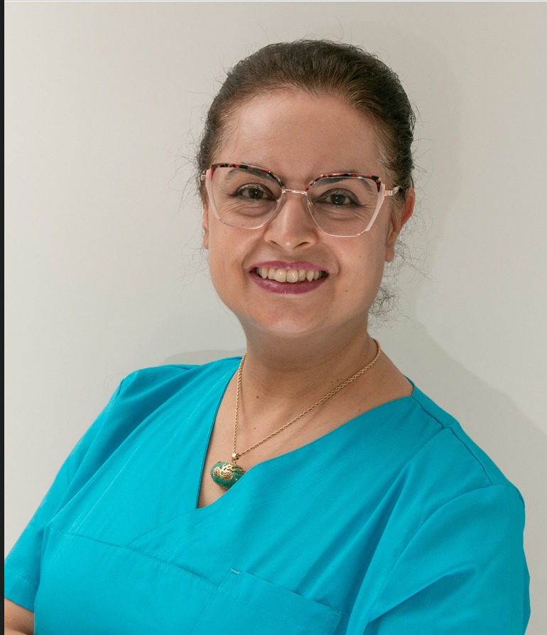 Dr. Maryam Nazary, Zahnärztin, lächelnd in türkisfarbener Praxiskleidung